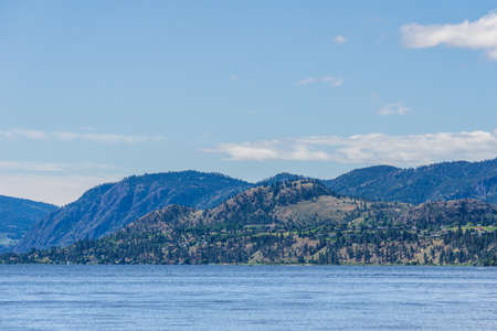 calm morning lake in British Columbia Canada blue sky with white cloudsの写真素材