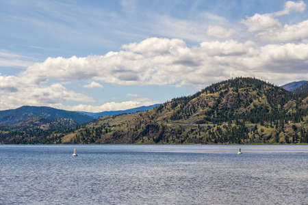 calm morning lake in British Columbia Canada blue sky with white cloudsの写真素材