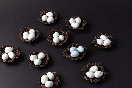 small Easter eggs in chocolate nests on a black background decoration.の写真素材