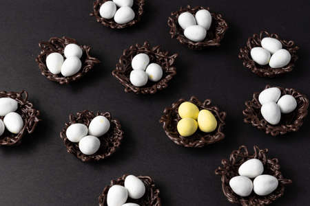 small Easter eggs in chocolate nests on a black background decoration.の写真素材