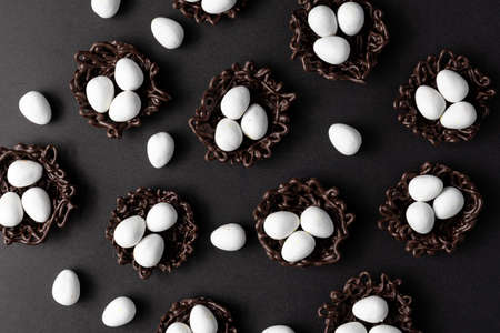 small Easter eggs in chocolate nests on a black background decoration.