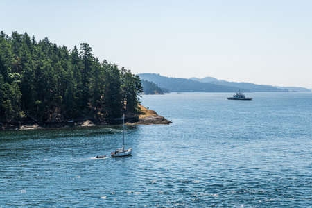 VANCOUVER, CANADA - JUNE 29, 2021: strait of Georgia with shore of islands covered with green forest ferry boat on the water.のeditorial素材