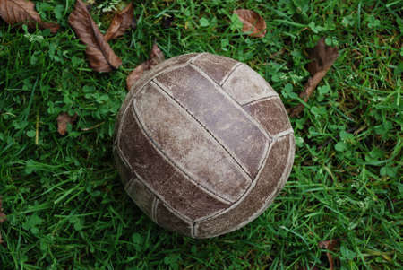 Old brown volleyball ball on green grassの写真素材