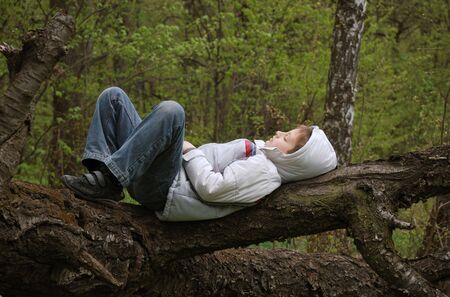 Boy lying on tree. Rest in forest. Silence.の写真素材