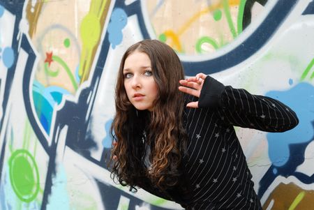 Young cute girl with long dark hairs. Graffiti wall. Fall. Autumn. Outdoor session.  の写真素材