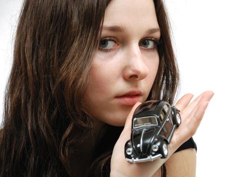 Face of young model with long hair and tiny car in hand, close-upの写真素材