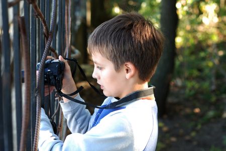 Boy concentrated holds a black digital camera in handsの写真素材