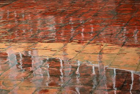 Wet shining surface of red pavement, colours, patterns and reflections