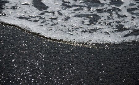 Tranquil sea wave with shining foam and transparent ripple, close-up, marine backgroundsの写真素材