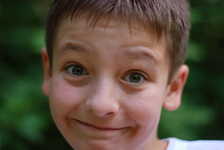 Frank face of light boy with eyebrows elevated and wide smile, close-upの写真素材