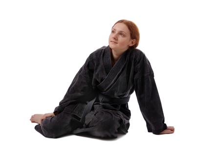 Barefooted girl in black uniform sits on the floor, isolated on whiteの写真素材