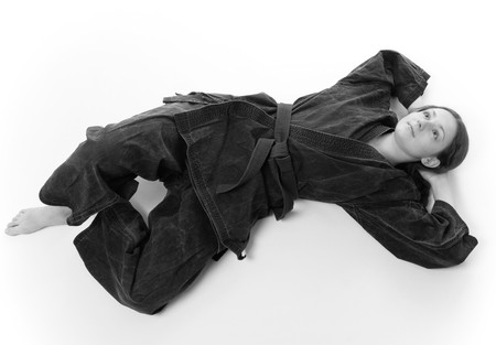 Barefooted girl in black uniform lies flat on back in the floor, hands thrown and legs crossed, white-and-blackの写真素材