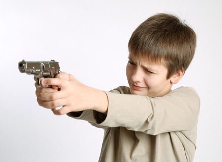 Pre-teen boy aiming a silver pistol, concentrated expression of child faceの写真素材