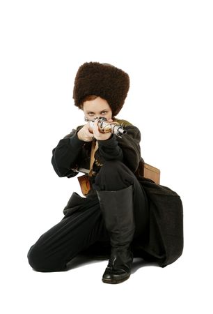 Young woman is wearing vintage uniform of Russian foot Cossack in time First World War. Russian Cossak is squatting and aiming a rifle at camera. She is dressed in woolen greatcoat, fur cap and boots. の写真素材