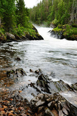 Rapids of Kitkajoki river are photographed near waterfall Jyrava. In the foreground there are wet stones and clear water. The picture is made during the hiking trail of the Little Bear's Ring.の写真素材