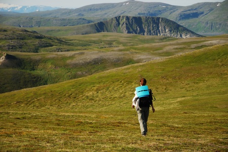 Woman is walking in the green mountains of summer Soroya. She is alone. She is carrying a rucksack....