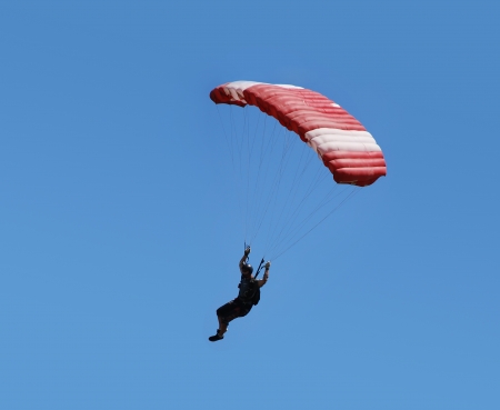 Parachutist with red parachute is flying in the blue sky.の写真素材