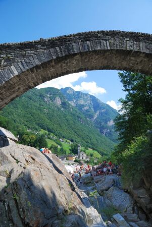 A lot of people are resting on the stones of riverside. Mountain river Verzasca flows through the green valley of Swiss Alps.のeditorial素材