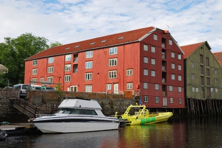 Wooden warehouses on stilts by the wharves are over the river with berth. The traditional view of Trondheim is made in summer.のeditorial素材
