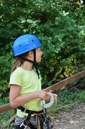 Preteen girl is wearing on the outfit for rope parkour. She is photographed in the summer forest.の写真素材