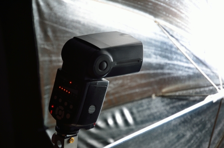 An electronic flash is against the background of the photographic umbrella flooded with light.の写真素材