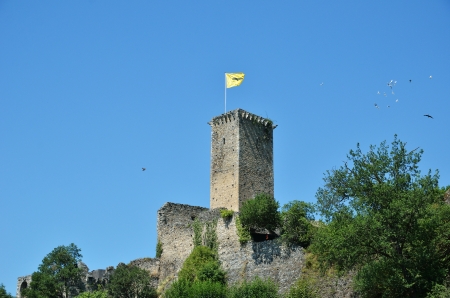 A tower with a flag dominates over the medieval fort against the background of the blue sky with birds flying. There is copy space.のeditorial素材