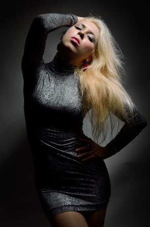 Blonde woman is posing and twisting her sexy body  She is wearing a slinky short dress の写真素材