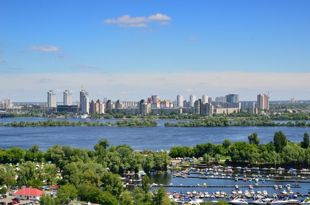 Wide river is dividing the city into right and left riverside  Remote residential districts recede into the distance  In the foreground there is a pier with various boats  の写真素材
