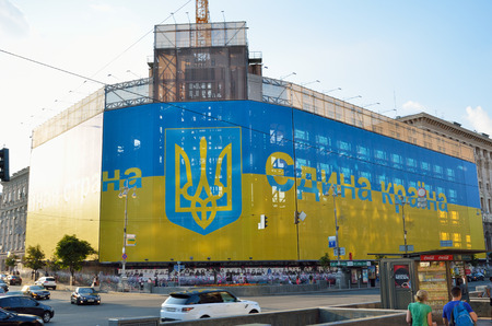 A large construction is wrapped with the Ukrainian national flag in the main street Khreshchatyk. There is the popular slogan \"all-in-one country\" on the banner.のeditorial素材