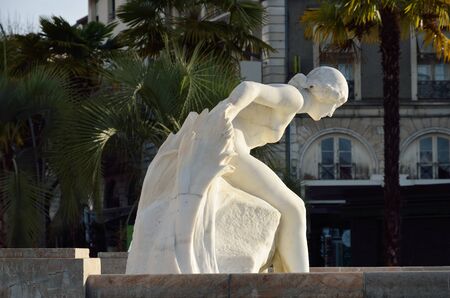 The Greek female statue is photographed against the green palm trees in the winter square of the French town Pau.の写真素材