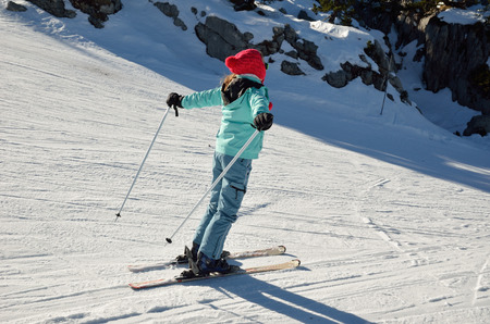 A skiergirl is sliding down on the ski run of compacted snow.の写真素材