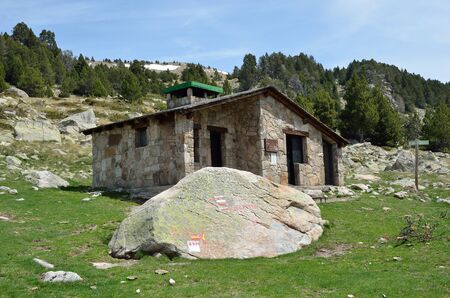 The tourist refuge and a big stone with markers in the upper part of the Vall-de-Madriu-Perafita-Claror.の写真素材