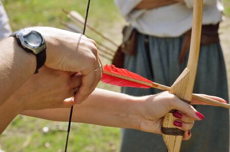 Female and male hands are holding a bow with an arrow.の写真素材