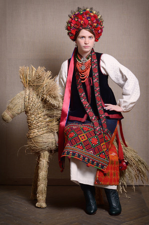 The young woman is sitting on the straw bull. She is wearing a Ukrainian traditional garment of wedding.の写真素材