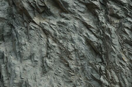 Rock vertical wall of the coastal cliff above the road in Cap Corse