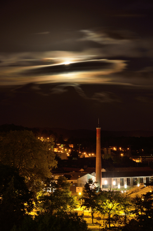 There are the green trees lightened with lanterns, windows illuminated and the full moon covered with clouds in the French town Pau.の写真素材