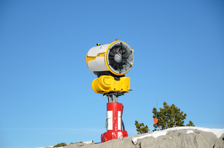 Snowmaking gun is photographed on the rock under the clear blue sky.の写真素材