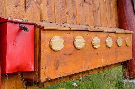 A metal postboxe near the row of wooden mailboxes on the wall