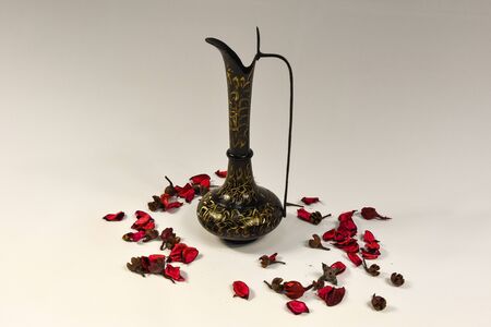 composition Indian vase brass vintage and violet flower petals on a white backgroundの写真素材