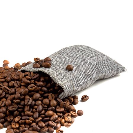 Roasted coffee beans spilling from a burlap sack isolated on white background with bokeh effectの写真素材