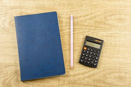 Notebook, pen, calculator on a wooden background Top view, flat layの写真素材