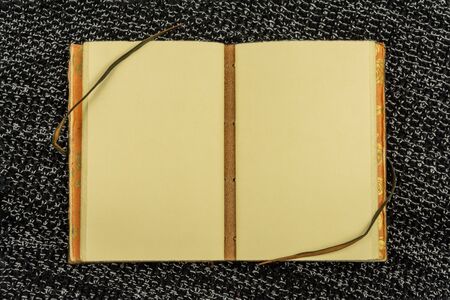 open vintage notebook on a background of knitted fabric in black top view flat layの写真素材