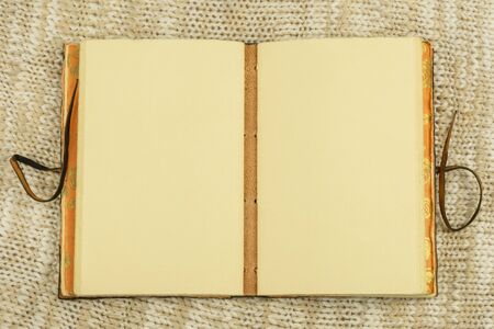 Open vintage notebook on beige knit fabric background top view flat lay