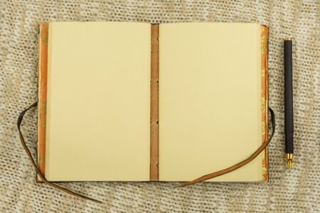 Open vintage notebook and pen on beige knit fabric background top view flat layの写真素材