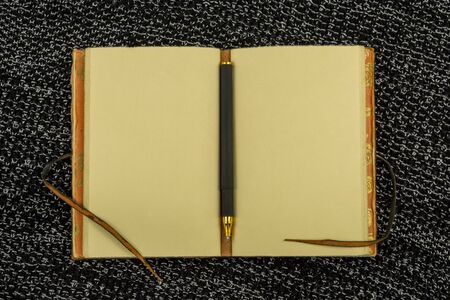 open vintage notebook and pen on a background of knitted fabric in black top view flat layの写真素材