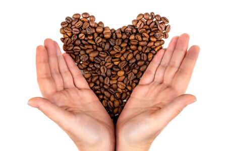 Roasted coffee beans in the palms in the form of a heart isolated on white background top viewの写真素材
