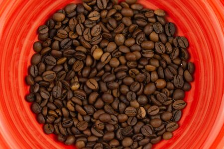 Roasted coffee beans in a red plate top view with copy spaceの写真素材