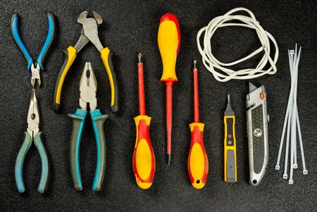 Electrician tool on black background. Top view. Flat lay