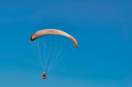 A man flying on a parachute with a motor above the sea surfaceの写真素材