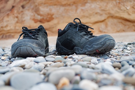 Dusty black shoes on the pebble beachの写真素材